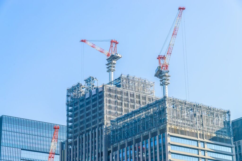 Construction site featuring multiple cranes with 3 industrial buildings under development in Canada.