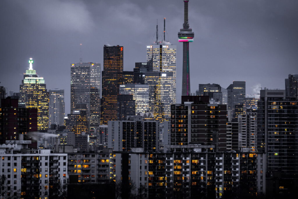 Illuminated Toronto skyline at night with city lights reflecting on Lake Ontario.